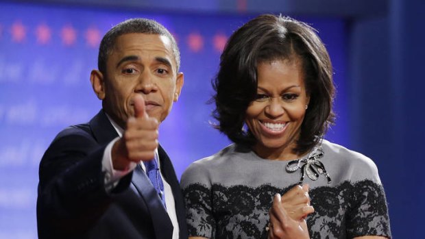 President Barack Obama, left, gives a thumbs-up as he is joined on stage by first lady Michelle Obama.