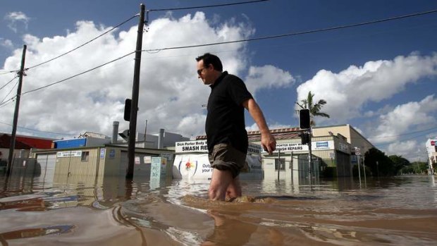 West End business owner Ross Clayton wades in knee high water on Montague Road during the 2011 flood.