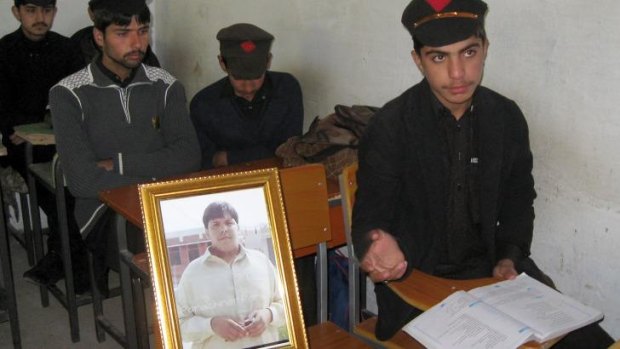 Pakistani students sit next to a picture of 17-year-old classmate Aitzaz Hasan, who died trying to protect their school in a remote village in Hangu district.