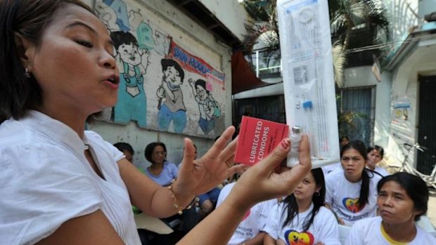 A Philippine health worker holds samples of contraceptives during a lecture to women in 2011.