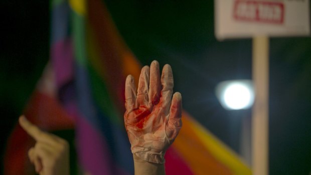 A protester holds up a glove covered in red during a protest in Tel Aviv against the violence towards the gay community.