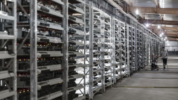 A technician inspects bitcoin mining machines at a mining facility in China.