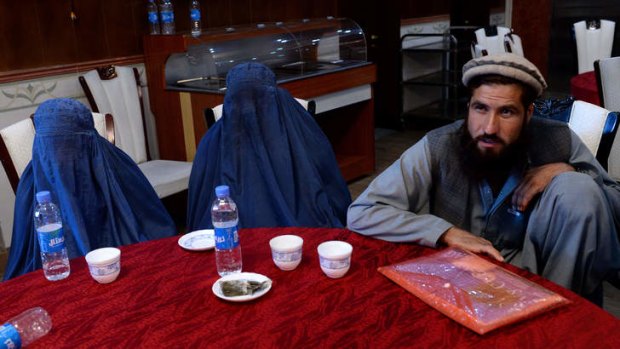 Two burqa-clad women with a male chaperone at the news conference in Kabul.