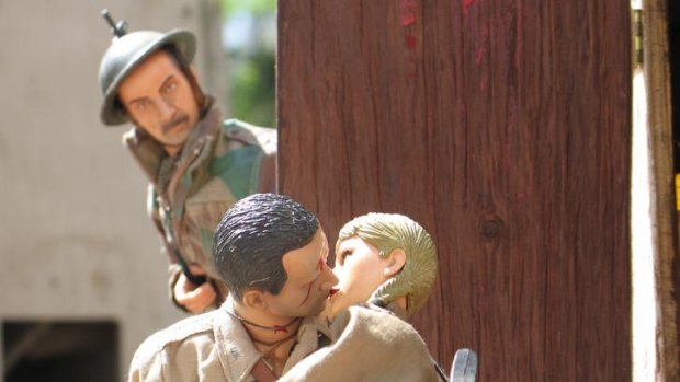 A soldier looks on as the Marwencol-ised Hogancamp and his bride steal a kiss.