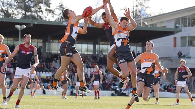 Matt Buntine and Taylor Adams, of the Giants, go up for a mark against the Demons at Manuka Oval in Canberra.