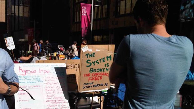 A passer-by reads the "Occupy Sydney" agenda list.