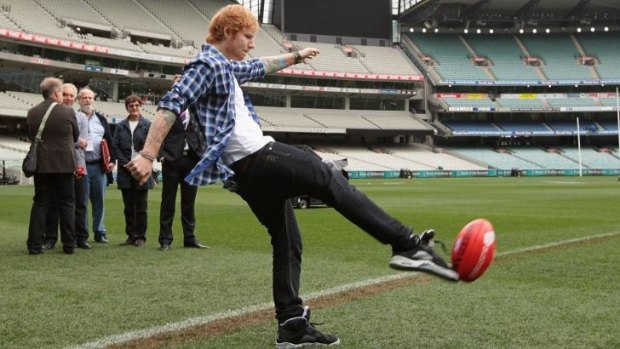 Ed Sheeran kicks a personalised 'Sheeran' football in honour of his upcoming AFL Grand Final performance.