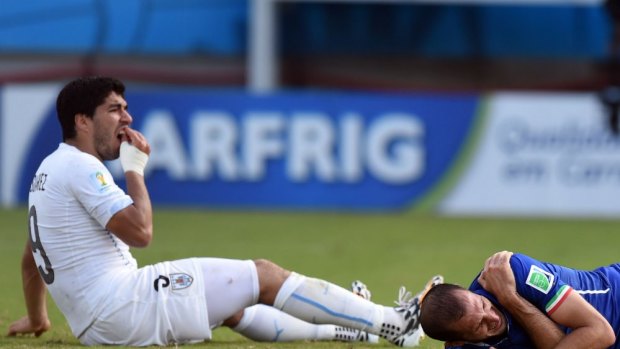 Uruguay's forward Luis Suarez (left) checks his teeth as  Italy's defender Giorgio Chiellini checks his shoulder for any damage after the alleged bite.