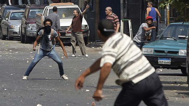 A local resident (rear left, facing camera) throws stones towards supporters of ousted President Mohamed Mursi during clashes in central Cairo.