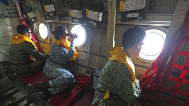 Military personnel look out of a Singapore Air Force plane during the search.