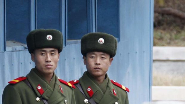 North Korean soldiers look across a concrete border.