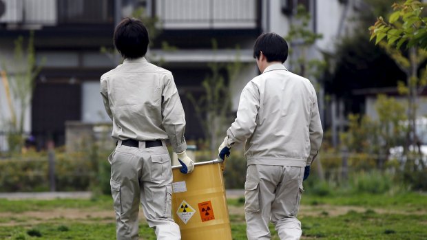 Workers of Tokyo's Toshima ward office carry away a container after it was dug up from the ground near playground equipment at a park in Toshima ward, Tokyo.