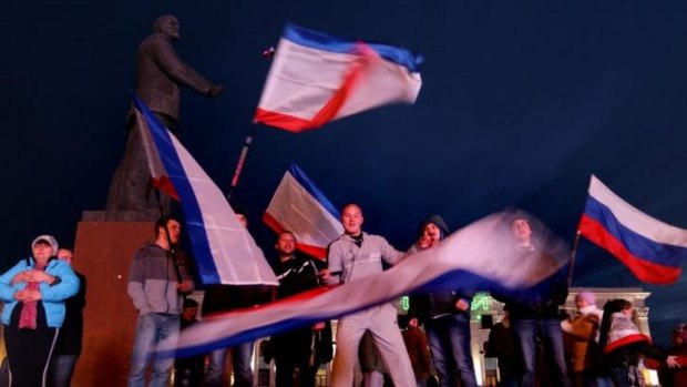 People wave Russian flags in Lenin Square in Simferopol to celebrate the preliminary results of the Crimean referendum.