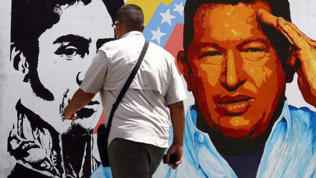 A man walks past a mural portraying the Venezuelan flag, President Hugo Chavez and South American liberator Simon Bolivar.
