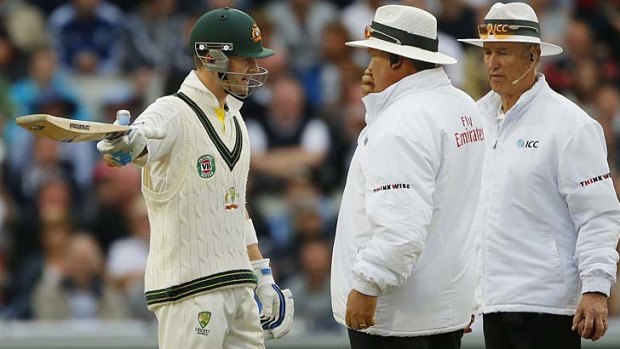 Australia's Michael Clarke talks with umpires Marais Erasmus (centre) and Tony Hill after they suspended play for bad light.