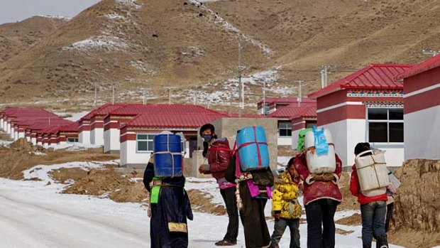 Tibetan girls carry water to their new homes in a resettlement village.