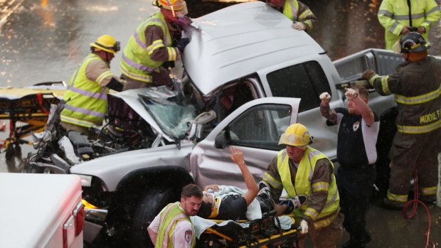 The driver of a pickup truck that crashed in severe weather on Interstate 35 gestures to his rescuers after being cut from the truck in Moore, Oklahoma.