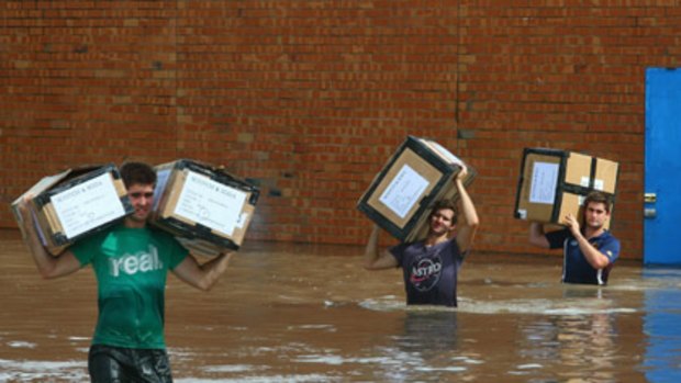 Residents help remove stock from a Brisbane business hit by the floods.