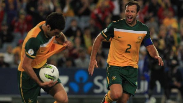 How sweet it is ... Lucas Neill watches Mile Jedinak celebrate after scoring against Oman last night. The Socceroos are now just one win away from the next round of qualifying for the World Cup in 2014.