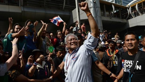 Thai protest leader Suthep Thaugsuban (C) raises his fist as anti-government protesters march in downtown Bangkok as part of their ongoing rallies.