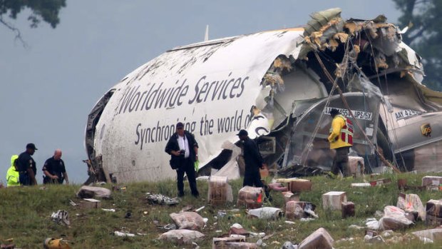 Investigators look through debris of a UPS A300 cargo plane after it crashed on approach to Birmingham, Alabama.