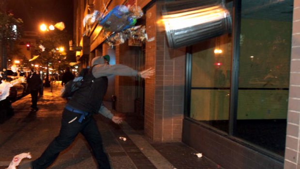 Verdict anger: A man throws a trash can at the window of a building during a protest after George Zimmerman was found not guilty.