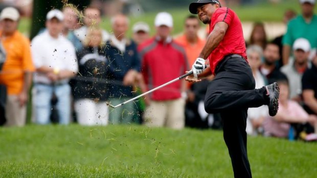 Tiger Woods hits out of the rough at Firestone Country Club on Sunday..