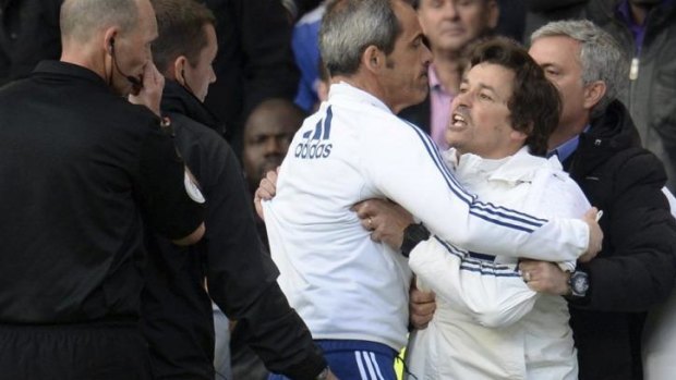 Mourinho (R) holds back assistant coach Rui Faria (2nd R) after he was sent off by referee Mike Dean (L).
