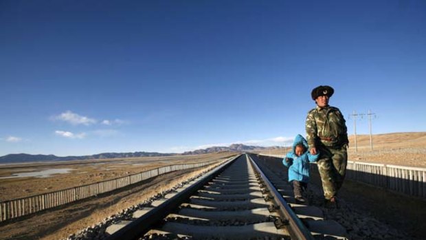 Top of the world ... a man walks along the Qinghai-Tibet railway track with his daughter.