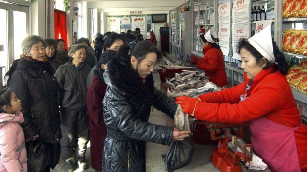A woman receives fish as a gift from the recently deceased leader Kim Jong Il, while others wait.