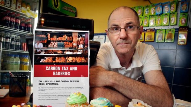 Robert Powell in his bakery in Frankston with a poster sent out by Tony Abbott's office. Displaying the posters could lead to a fine for misleading customers, however inadvertent.