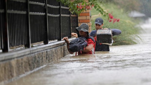 Residents wade through floodwaters in Houston on Sunday.