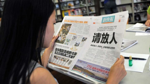 A woman reads the New Express newspaper that carried a full-page editorial with headline "Please release our man", in a library in Guangzhou, south China's Guangdong province.