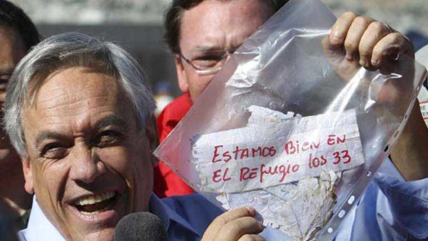 Chilean President Sebastian Pinera holds up a plastic bag containing the  message "We are OK in the refuge, the 33 miners".