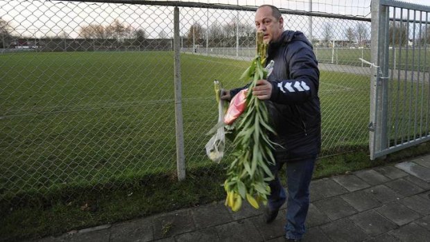 A man places flowers on the pitch of the football club Buitenboys.