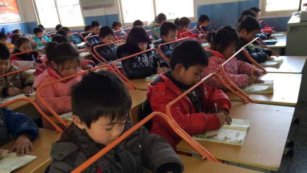 Chinese children read books with special desks equipped with iron bars to help them protect their eyesight.