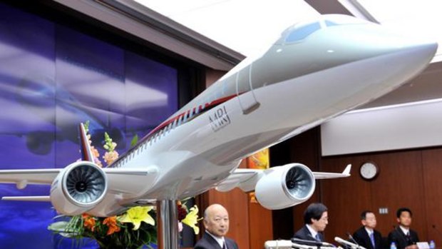 Mitsubishi Heavy Industries president Kazuo Tsukuda (centre) displays a scale model of the company's passenger jetliner.
