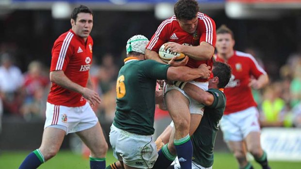 Jamie Roberts of the British and Irish Lions is tackled by Heinrich Brussow and Ruan Pienaar of the Springboks.