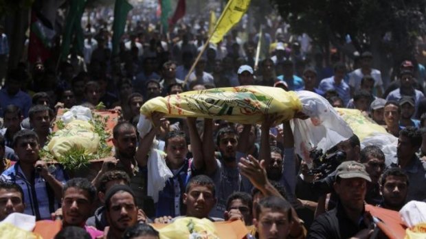 Palestinians carry the bodies of seven people killed in an Israeli air strike during their funeral in the Khan Younis refugee camp in the southern Gaza Strip. The bodies are wrapped in the yellow colours of the secular Fatah movement.