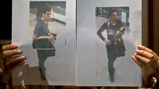 A Malaysian police official displays photographs of the two men who boarded the Malaysia Airlines flight using stolen passports. The man on the left has been identified as Pouria Nour Mohammad Mehrdad, a 19-year-old Iranian asylum seeker. The man on the right is yet to be identified.