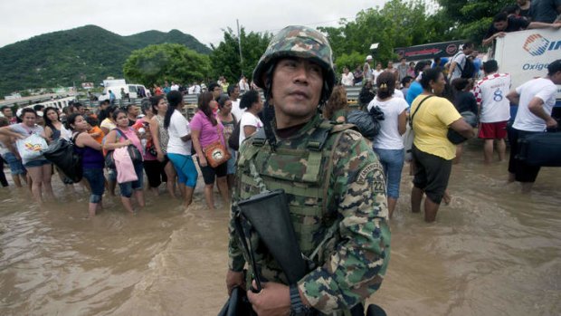 A Mexican Navy member stands guard in a flooded area of Acapulco, Mexico. The official death toll rose to 47 after the tropical storms, Ingrid and Manuel, swarmed large swaths of the country during a three-day holiday weekend.