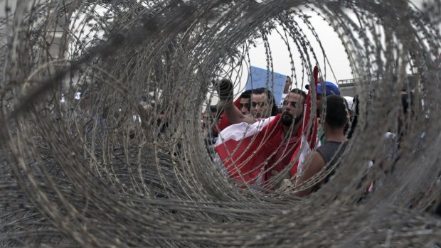 Lebanese anti-government protesters are seen through barbed wire in Beirut on Wednesday.