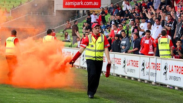 Security deals with a flare thrown by Dandenong Thunder supporters during the VPL grand final against Oakleigh Cannons.