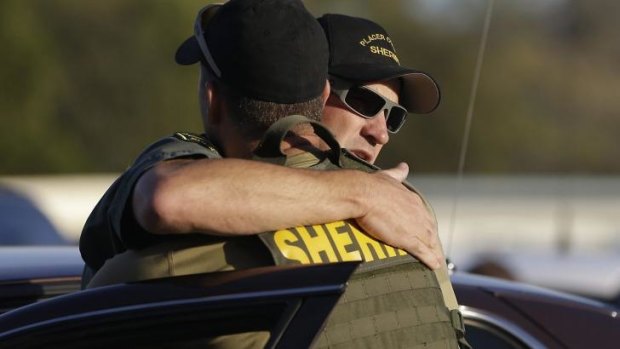 Two sheriff's deputies embrace after a gunman is arrested in California having killed two other deputies. 