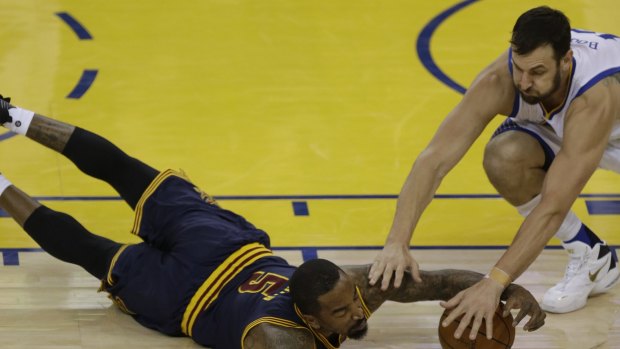 Cleveland Cavaliers guard J.R. Smith, left, reaches for a loose ball under Golden State Warriors centre Andrew Bogut during game one of the NBA finals in Oakland, California.