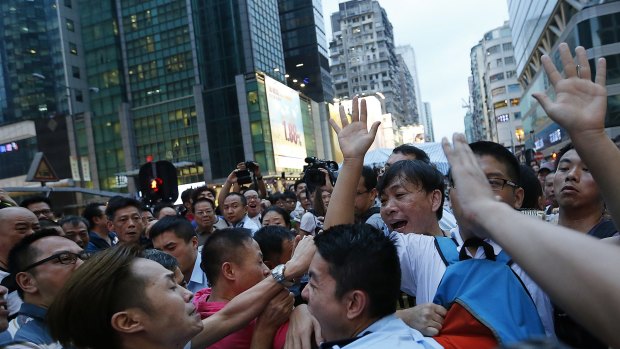 A local policeman scuffles with residents and pro-Beijing supporters as they try to attack a student pro-democracy activist in Kowloon's crowded Mong Kok district.