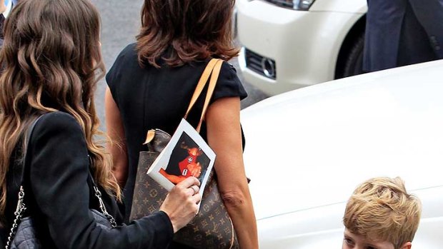 Jim's son Tiernan holds on to mum Sam's hand as the family prepares to leave the funeral service.