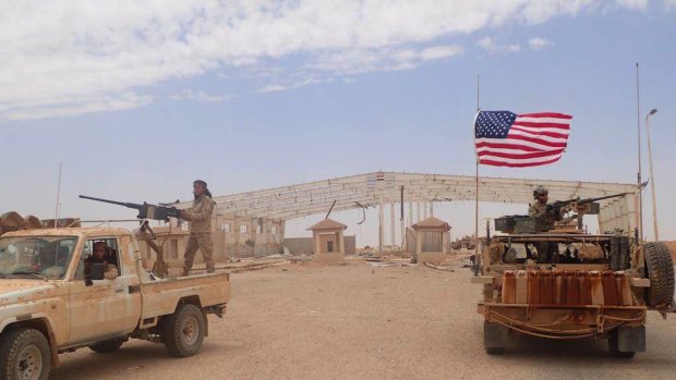 A US-backed anti-government Syrian fighter stands on a vehicle next of an American soldier who also stands on his armored vehicle, right, as they take their position at the Syrian-Iraqi crossing border point of Tanf, south Syria.