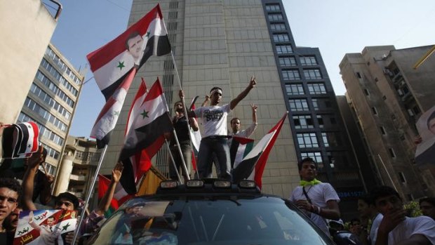 Syrians living in Lebanon flash victory signs and wave their national flags.