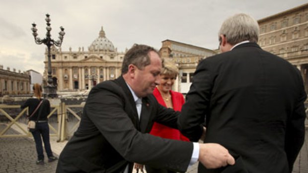 The hem of his garment ... Julie Bishop watches as Barnaby Joyce straightens Kevin Rudd’s coat in Rome.
